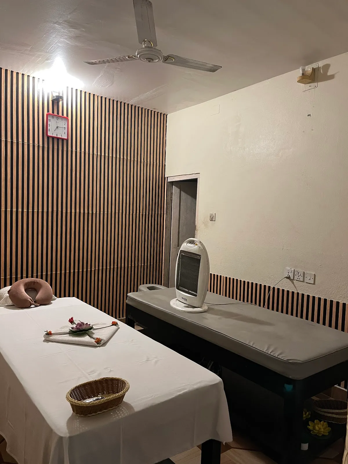 Treatment room with slatted wood panel wall and crisp white linen.